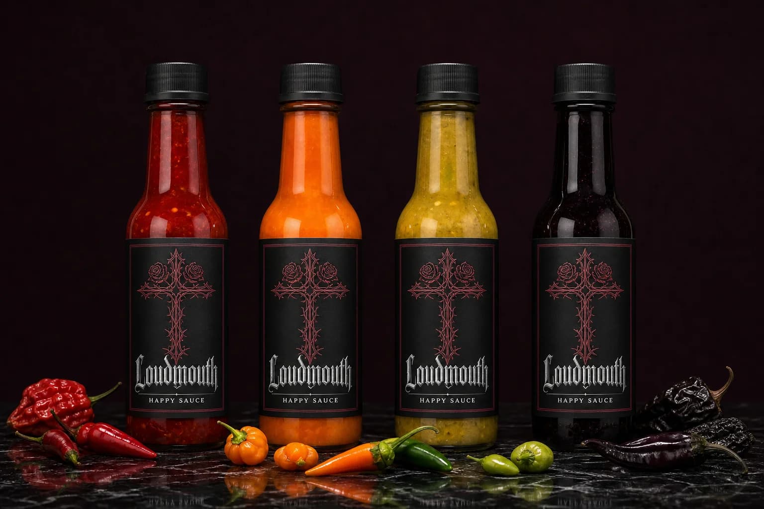 Four Loudmouth Happy Sauce bottles in a row, matte black blackletter labels, red, orange, gold and near-black sauces